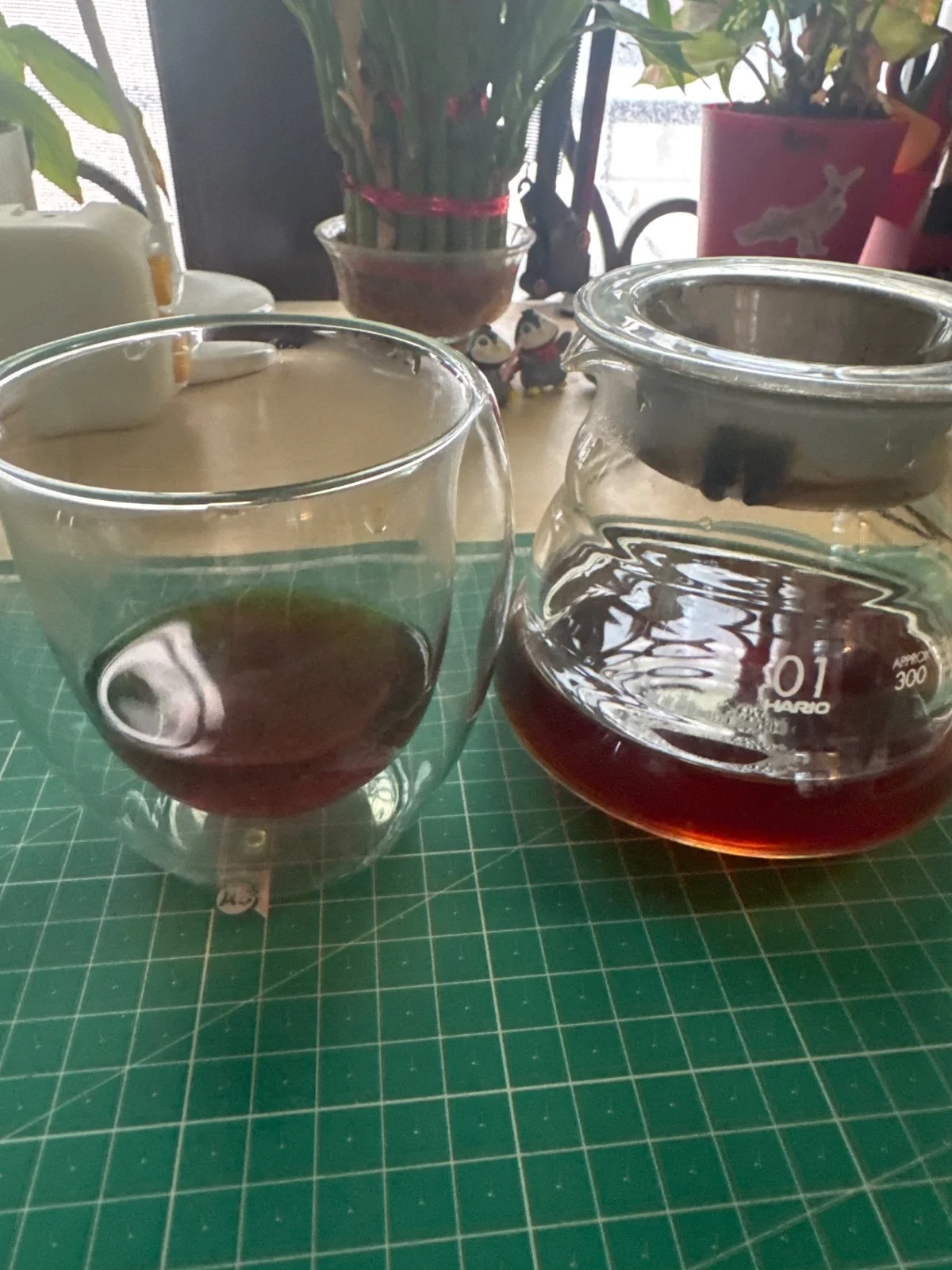 Freshly brewed filter coffee in a glass cup beside a glass server