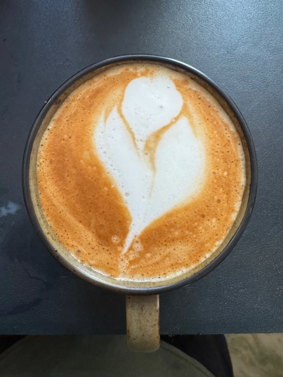 A homemade milk coffee with white latte art on a dark desk