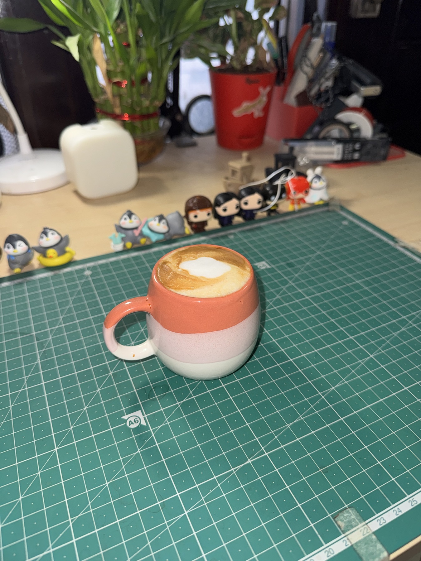 A homemade cortado in a coral, pink, and cream ceramic cup on my desk